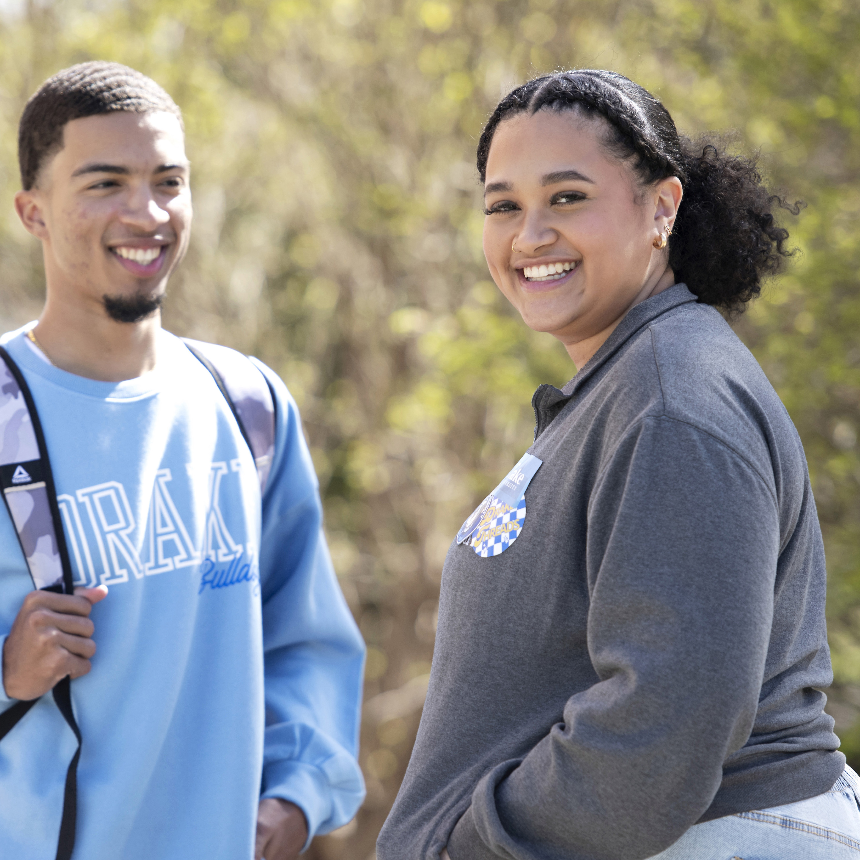 Two Drake students, one in a school sweatshirt, have a conversation outdoors