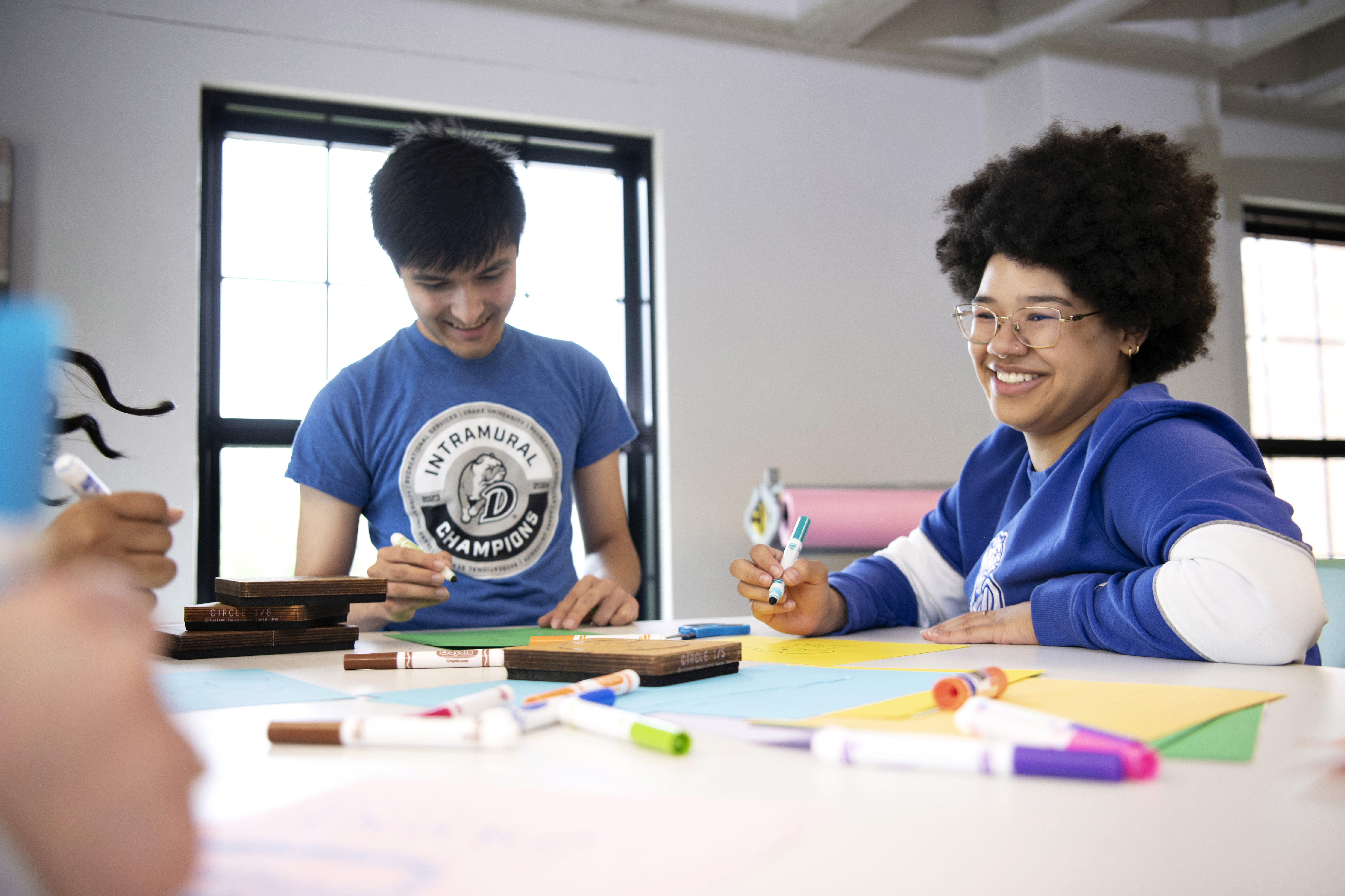 For a club activity, Drake students sit around a table with markers and paper to make fliers