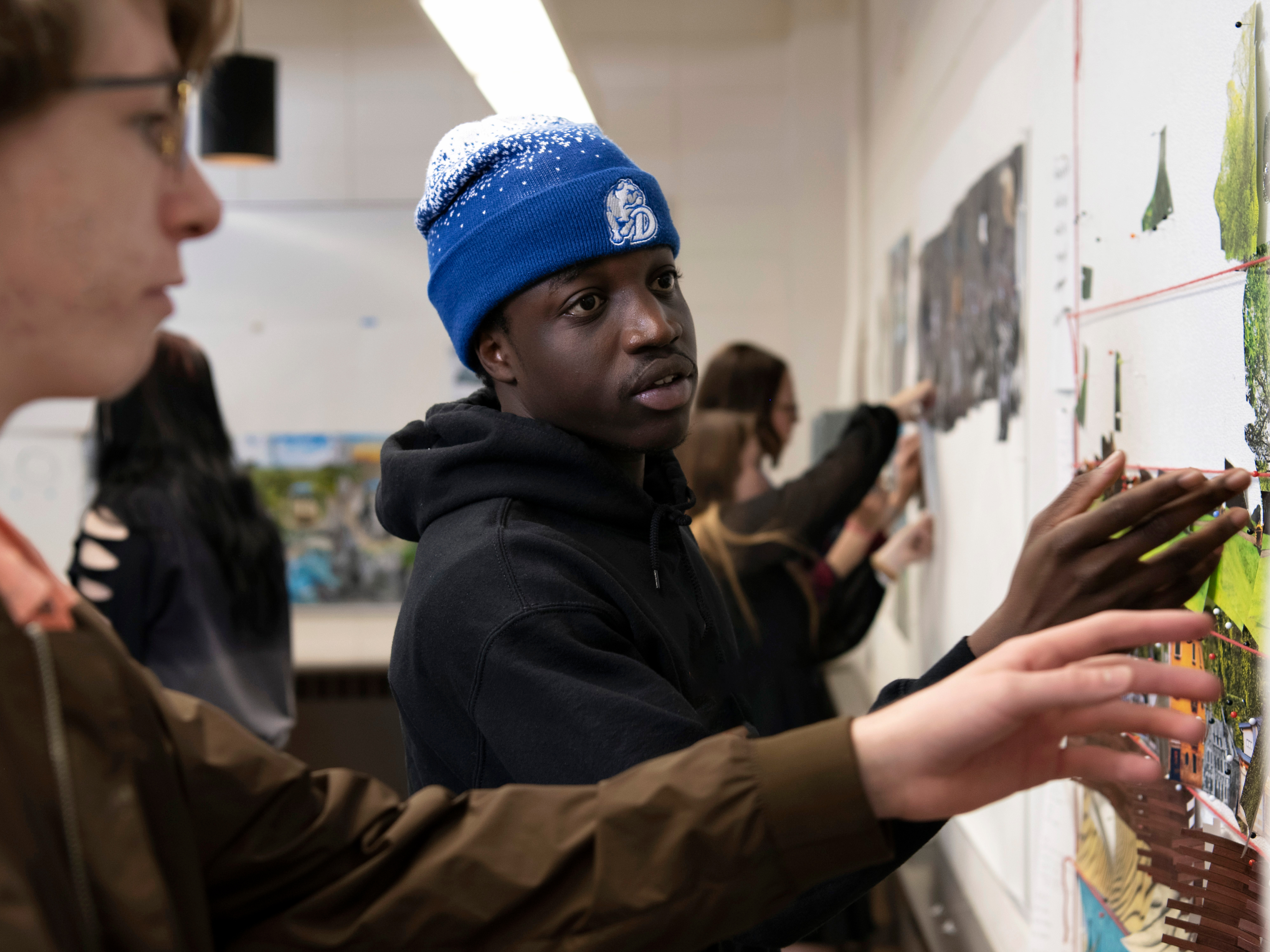 Drake students measure and align artwork on a classroom wall for a community service project