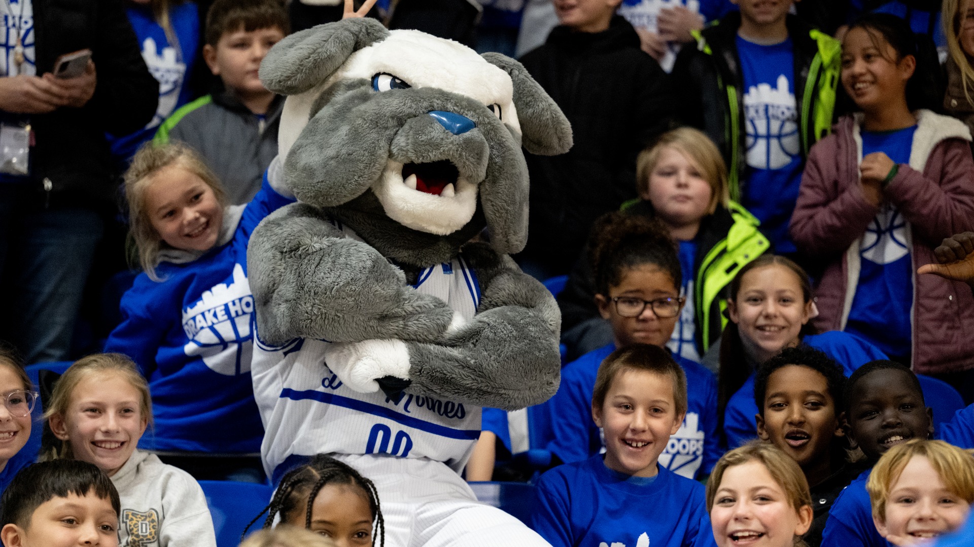 The Griff mascot crosses its arms in a crowd of children wearing blue during a community event hosted by Drake