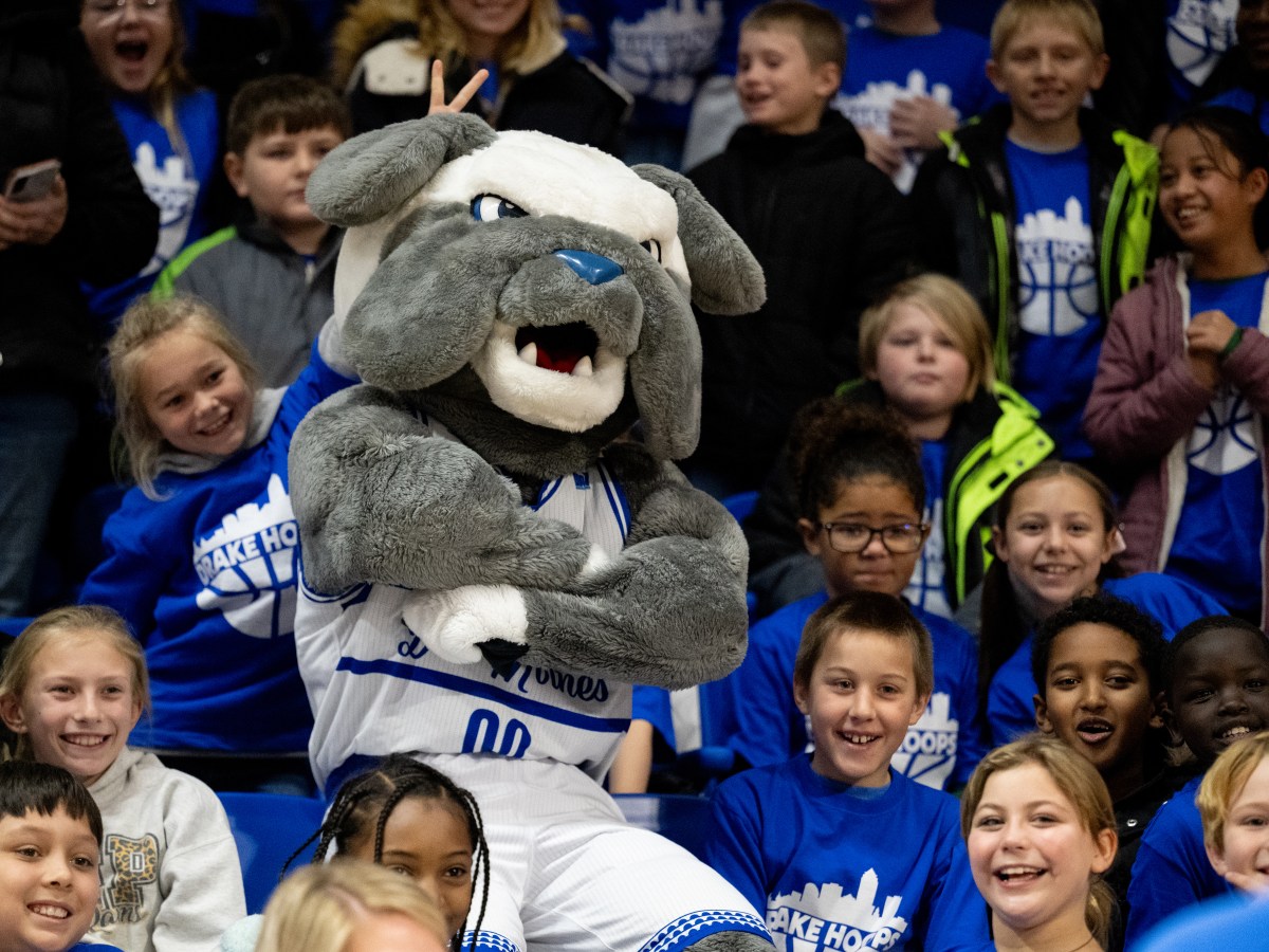 The Bulldog mascot stands cross-armed in a crowd of children during a Drake basketball game
