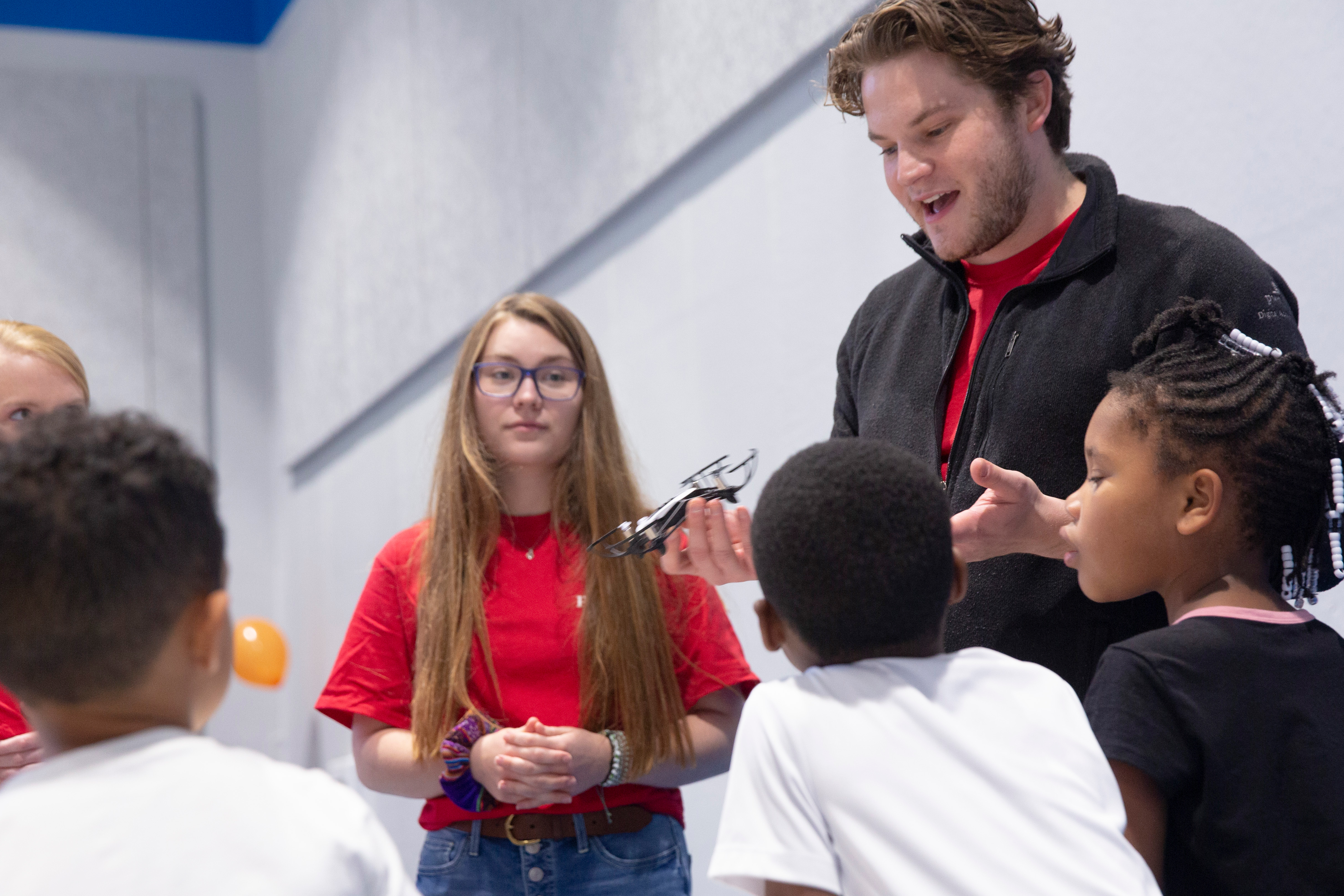 During a STEM event, a Drake student explains the function of a metal object held to a group of elementary schoolers