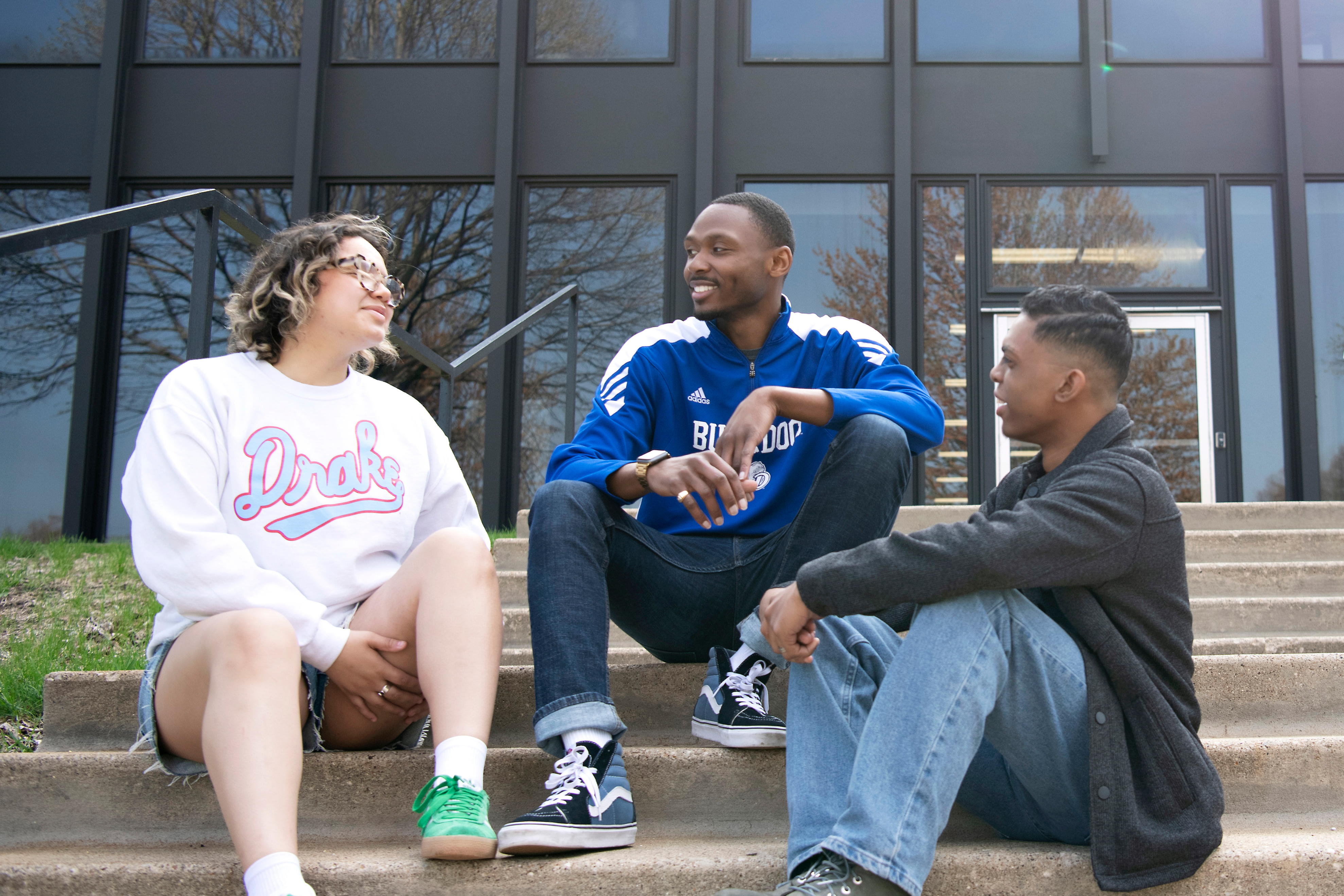 Three students from Drake's Bright College have a conversation on the front steps between classes