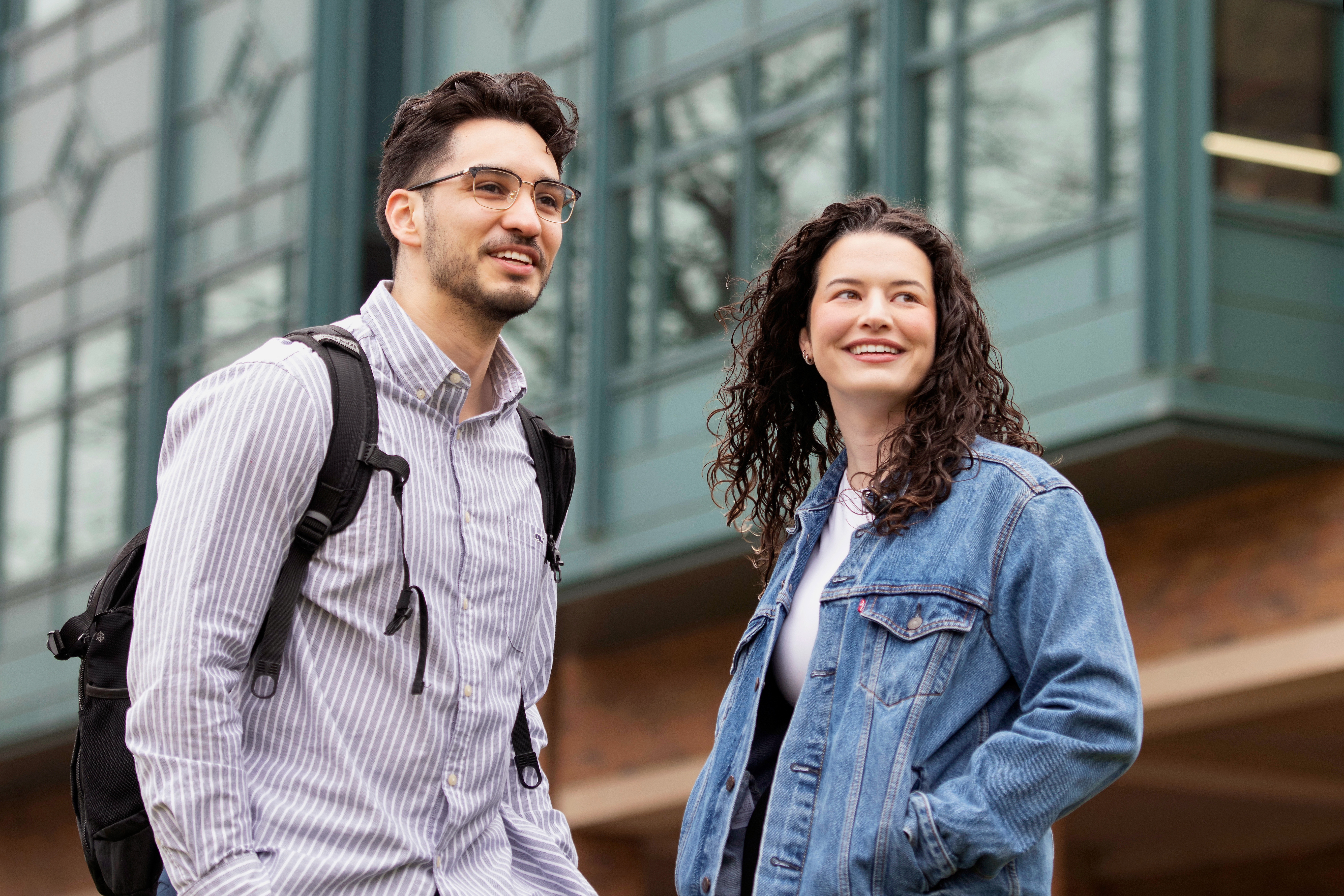 Two Drake Law students, one with a backpack, have a discussion outdoors before class