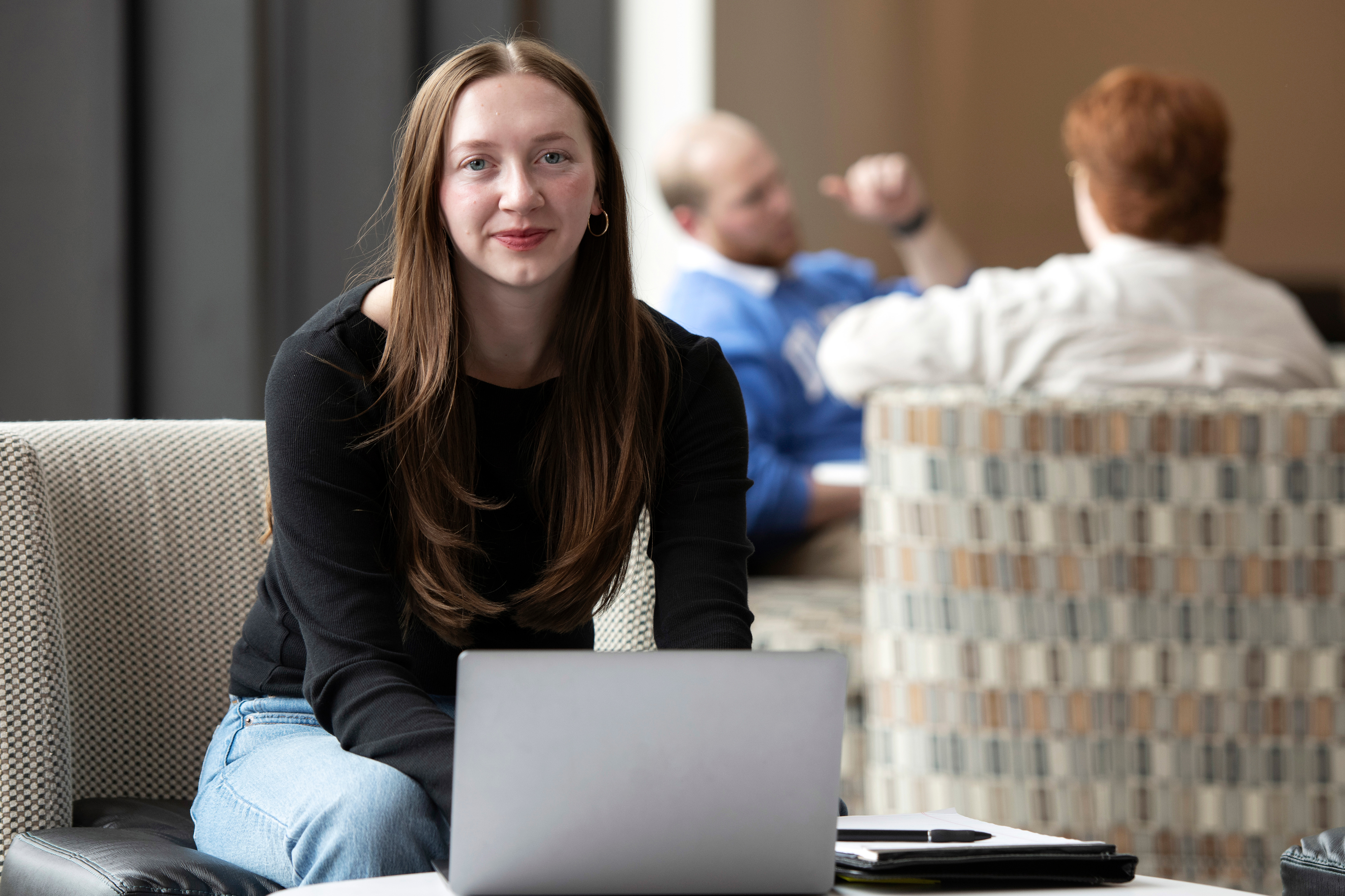 A Drake student logs in for online classes from a public space, laptop and notebook open on a table