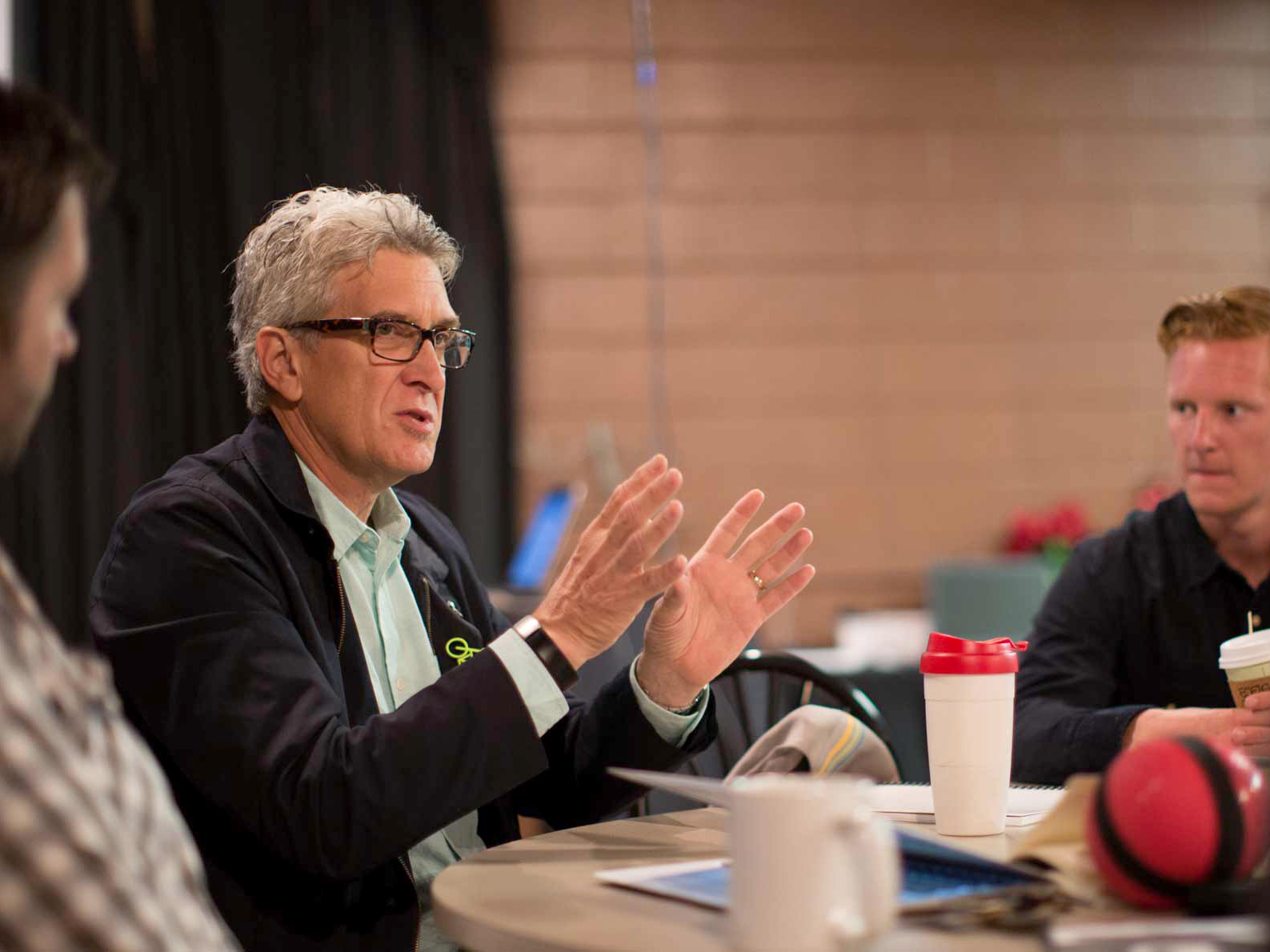 A Drake faculty member gestures while explaining a research concept to a table of students