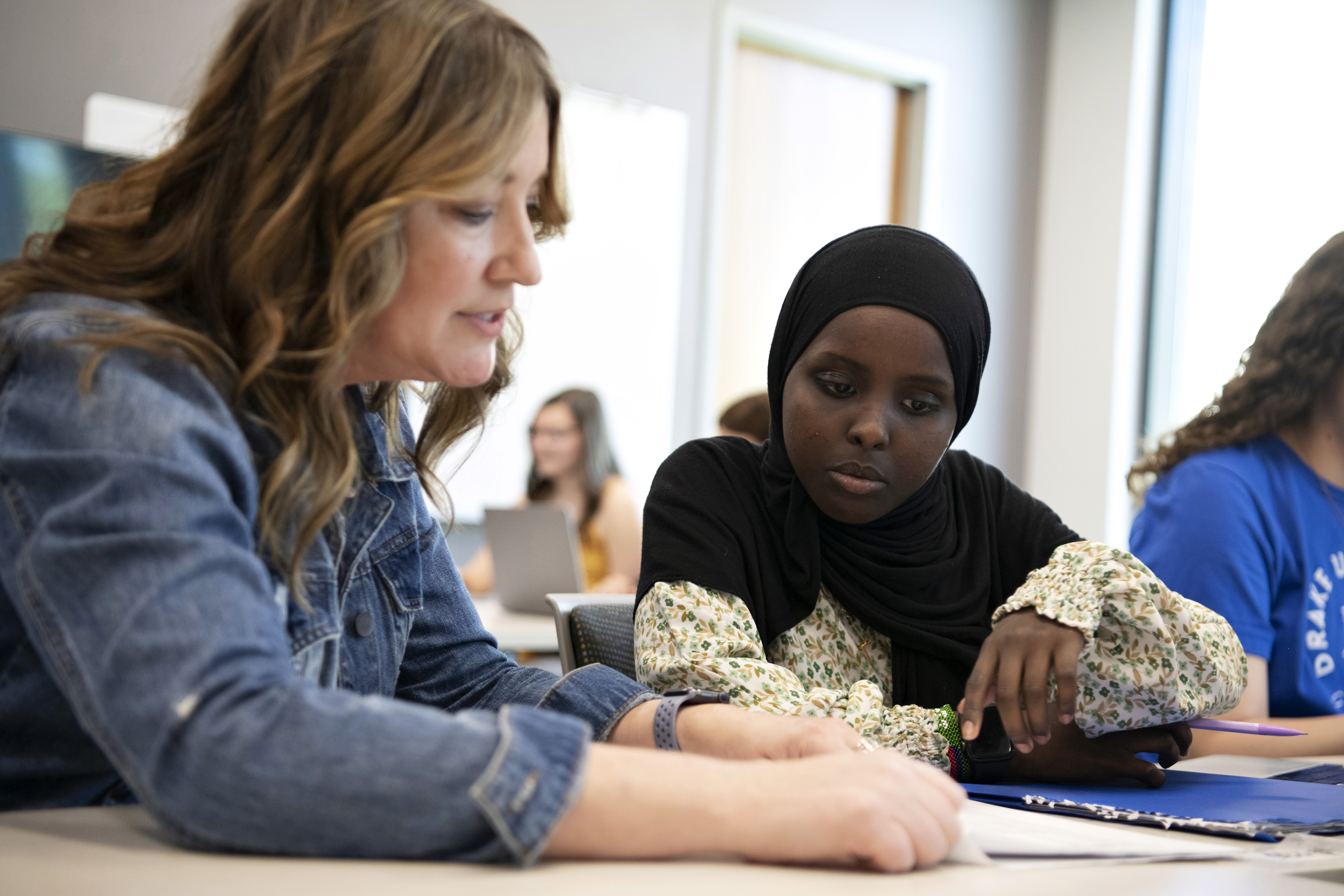 A member of Drake admissions team explains a document to an incoming first-year student seated next to them