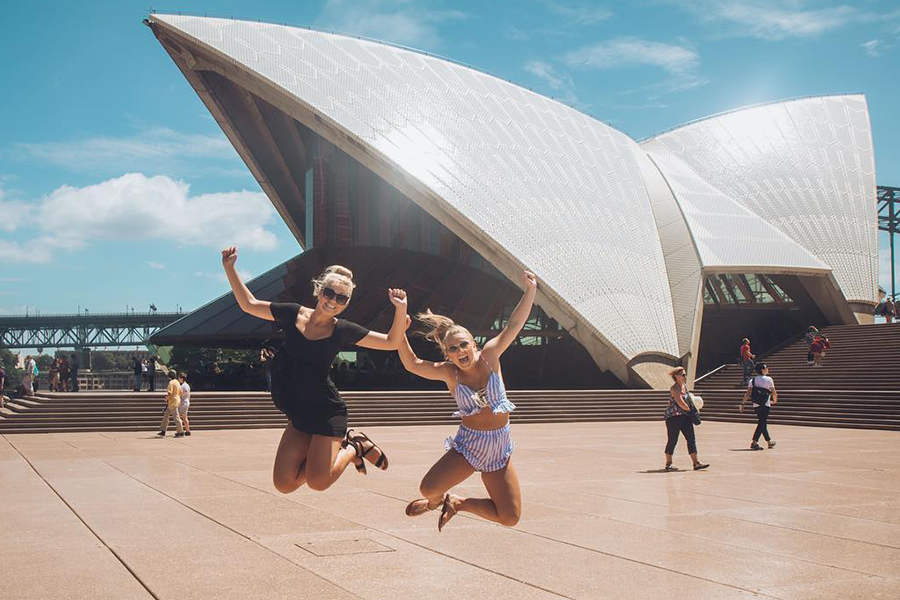 Two Drake student jump to excitedly click their heels in front of the Sydney Opera House during a study abroad trip