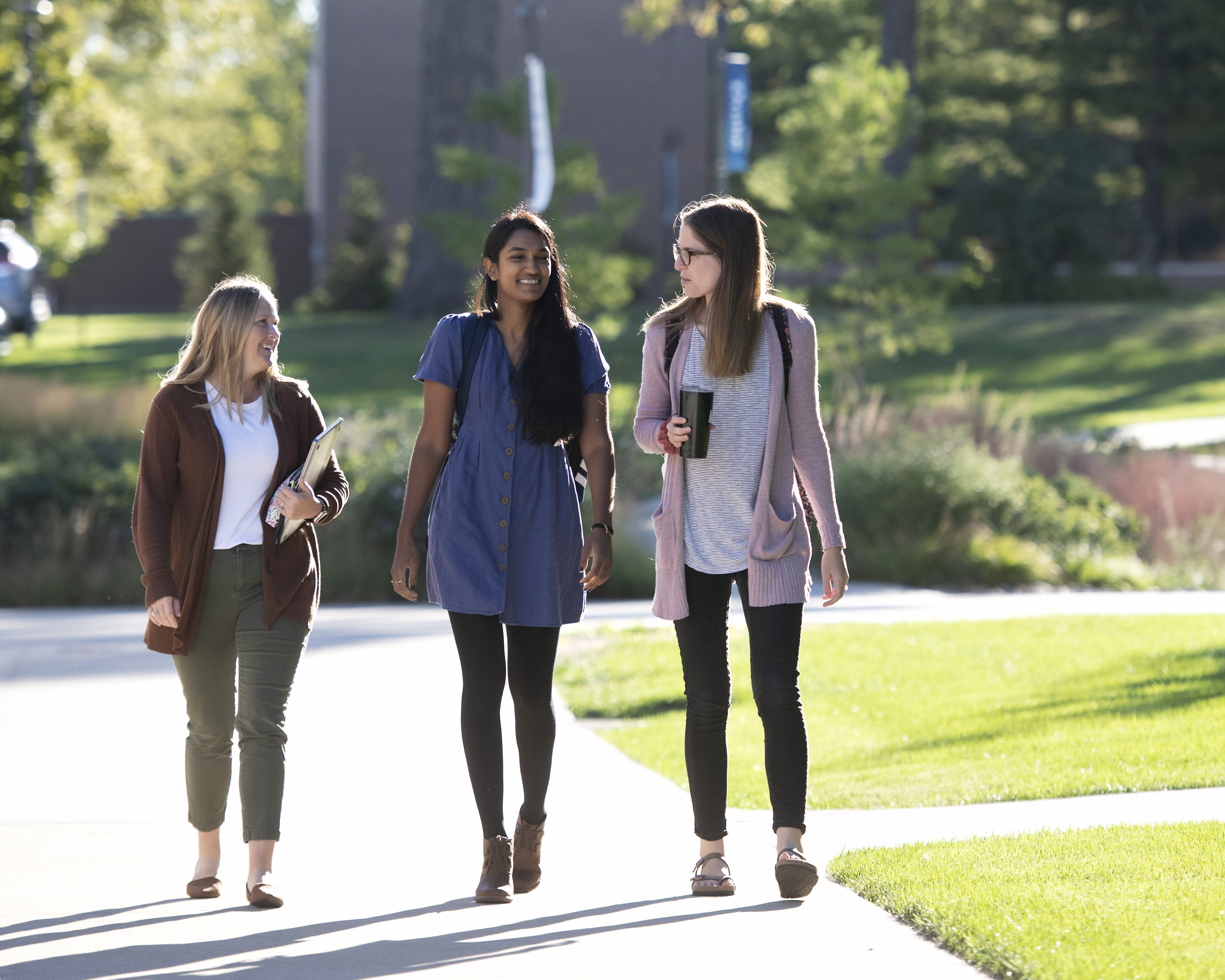 Three graduate students have a discussion while walking to class on Drake's campus