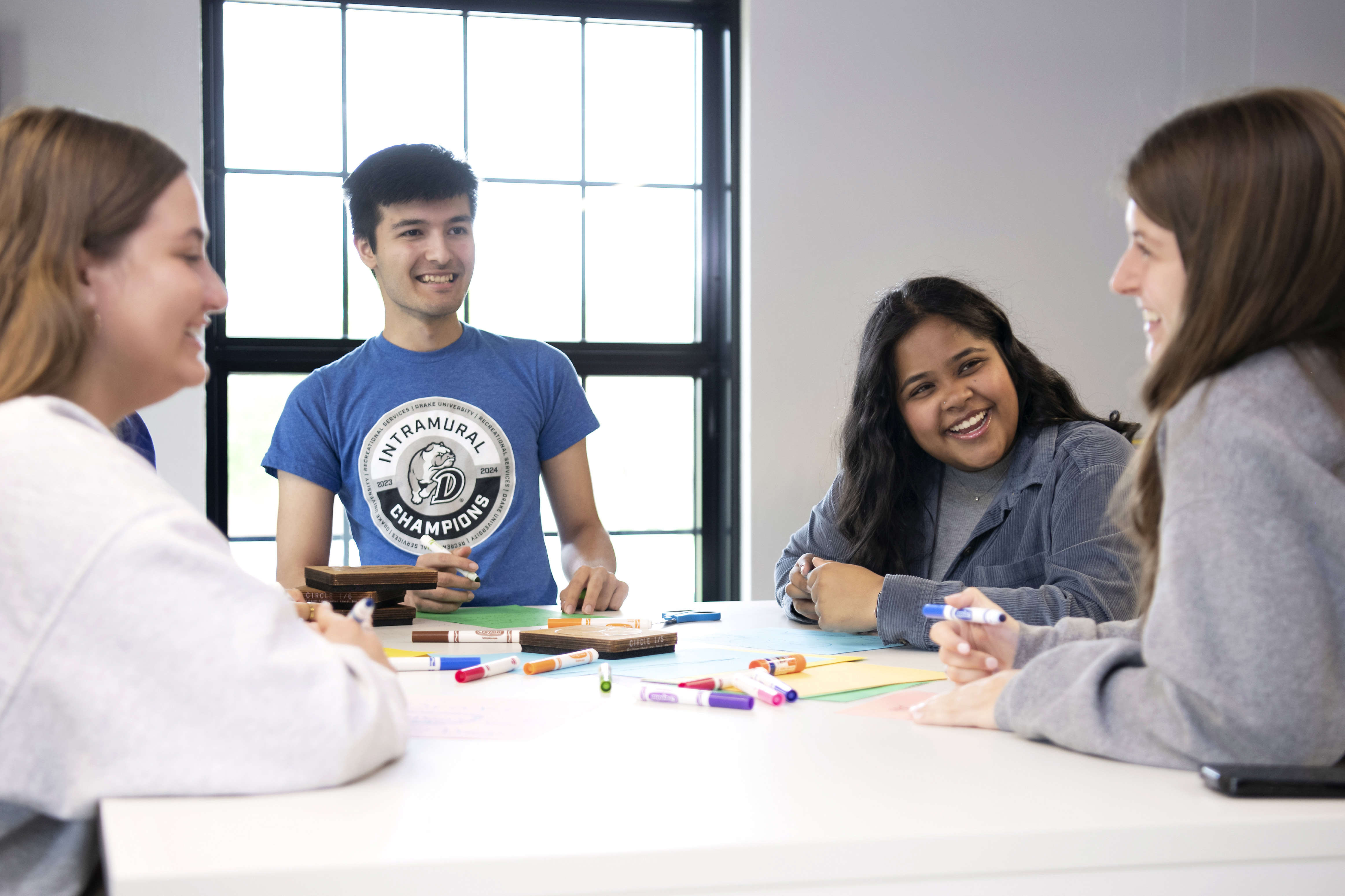 International students meet around a table at Drake for a group coloring activity