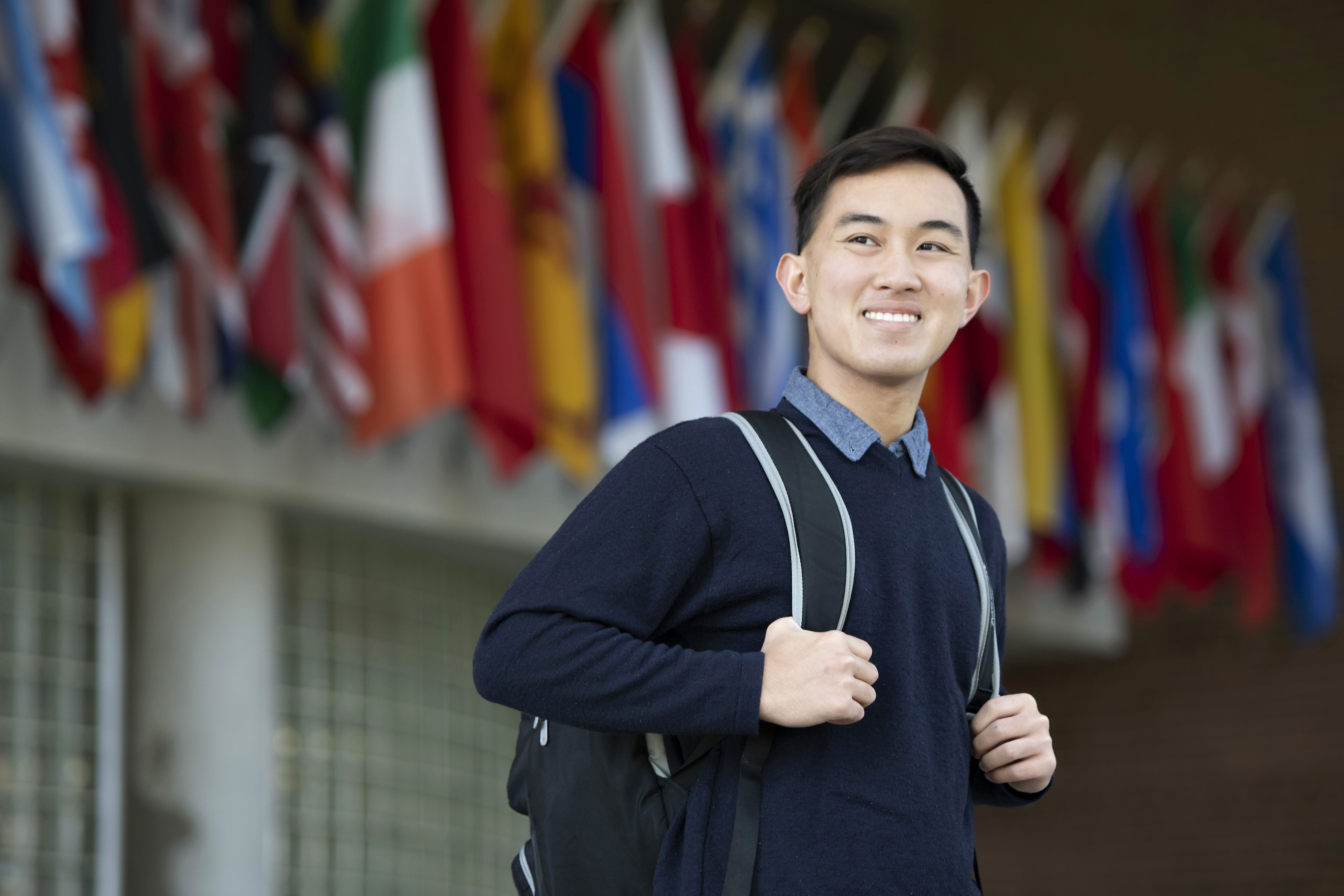 A student wearing a backpack stands and looks to the right in front of Drake's Zimpleman College of Business