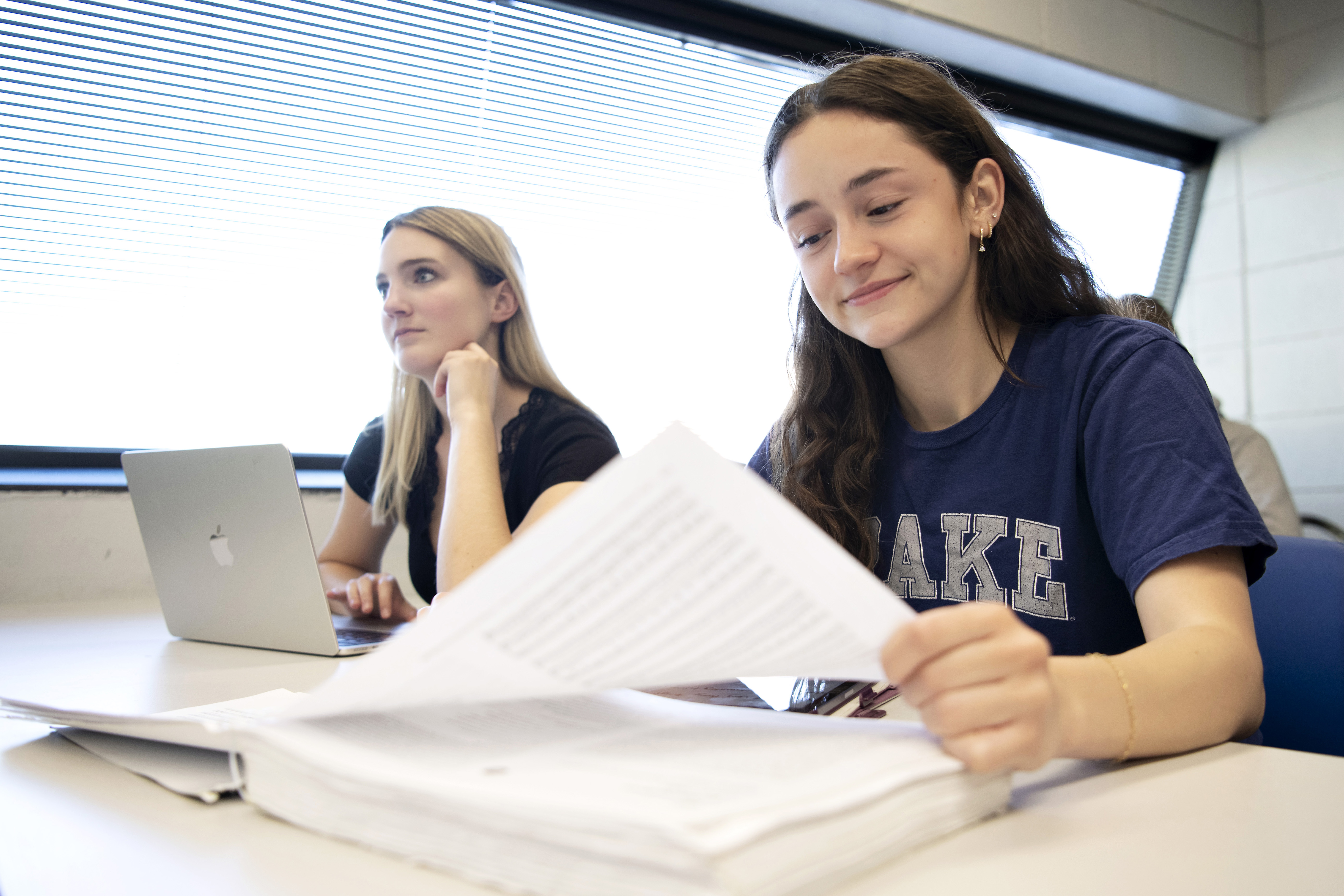 As one student reviews their notes, another stares ahead while sitting behind their laptop in a Drake classroom