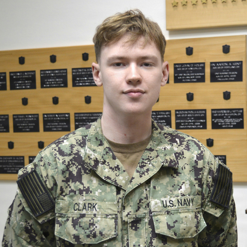 A student in U.S. Navy camoflauge attire looks at the camera
