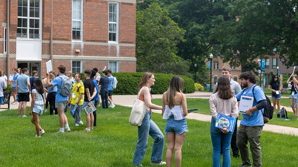 Students and student orientation leaders talking outside of Old Main during Summer Orientation.