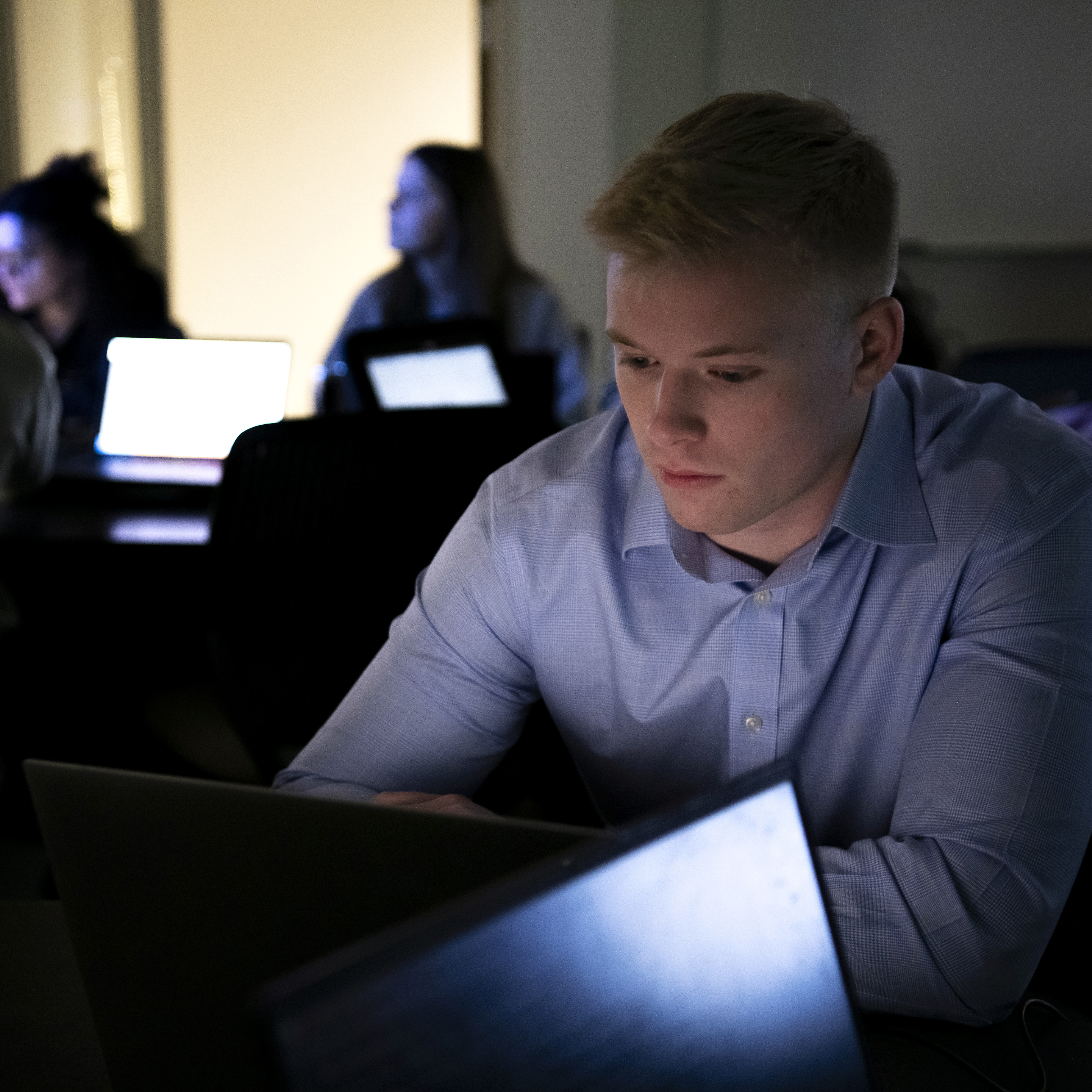 Drake students work on an activity on their laptops in a dark campus lab