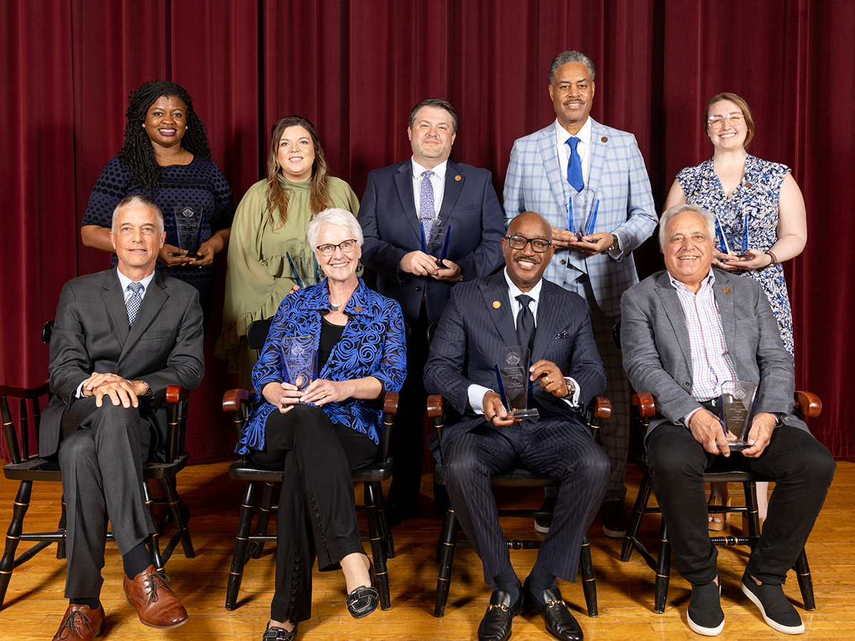 Drake alumni of varying ages sit or stand on stage during an award ceremony