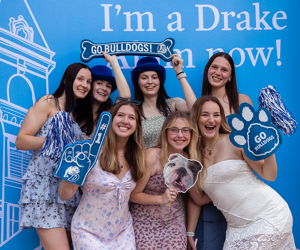 Group of female students standing in front of a backdrop that says "I'm a Drake Alum now!"