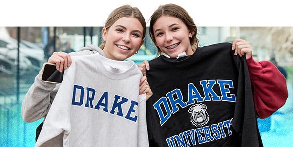 Two female students holding up Drake crewnecks.