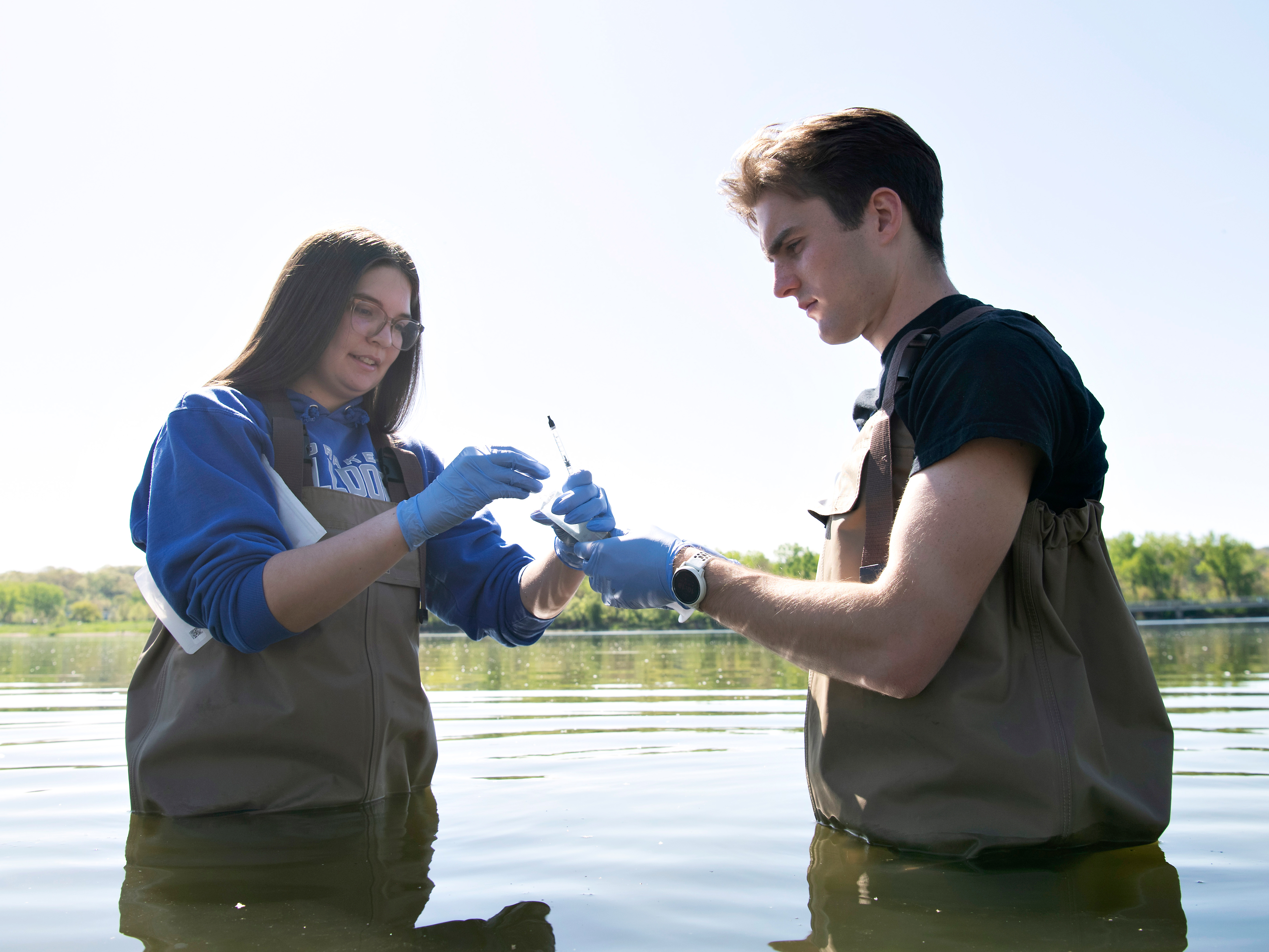 For a research project, two Drake College of Arts and Sciences students wearing waders sample pond water