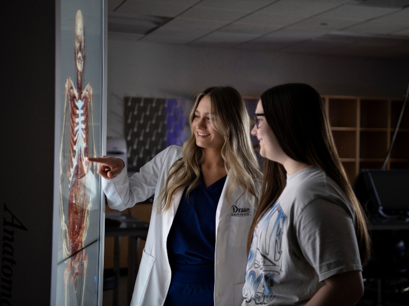 A College of Pharmacy and Health Sciences faculty member studies a lit anatomage table with a Drake undergraduate student