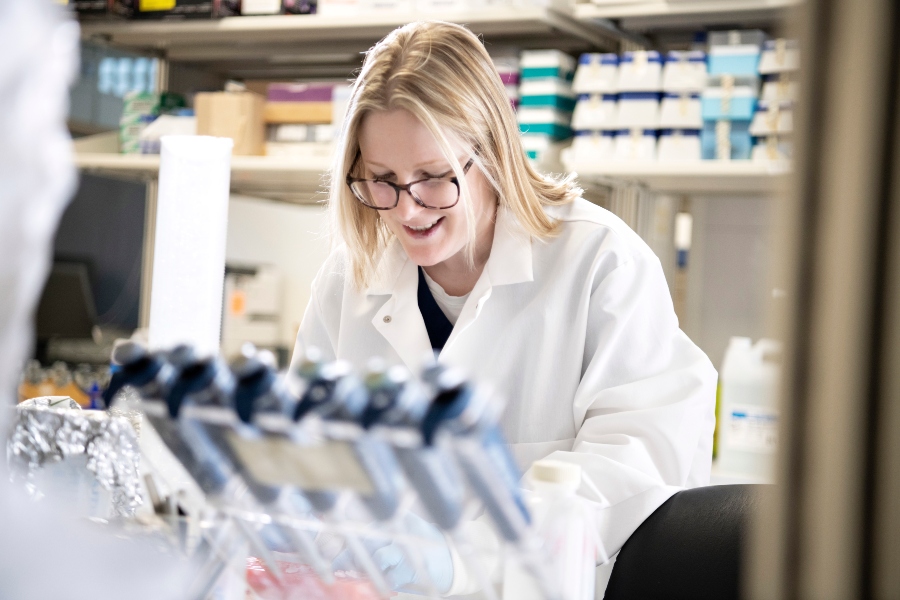 A Drake student in a lab coat conducts research in one of the College of Pharmacy and Health Sciences' labs