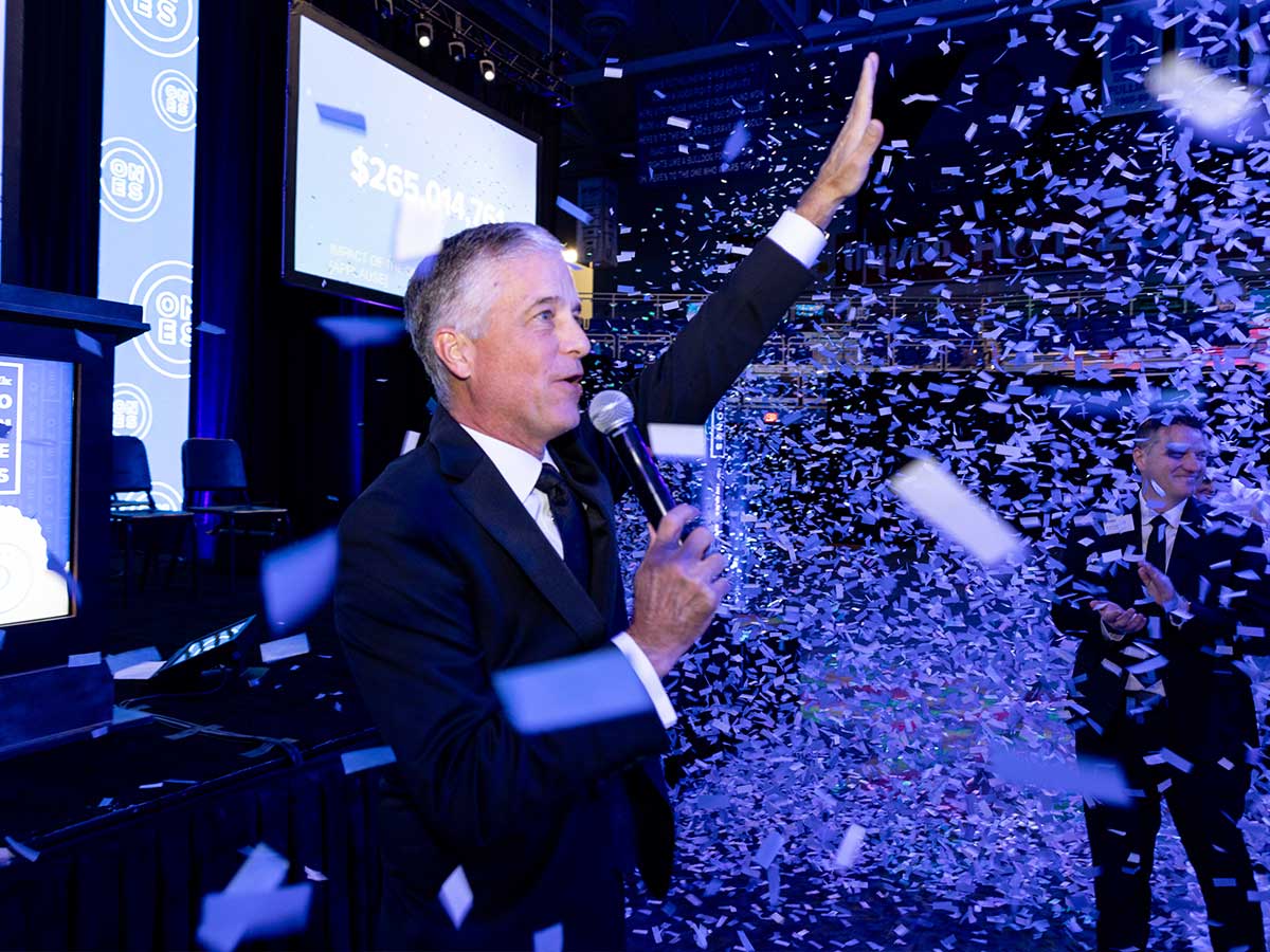 Marty Martin speaking into a microphone at FMDS at the close of the Ones Campaign with confetti flying around him.