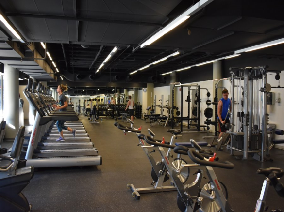 Individuals using workout equipment in the Underground Fitness center.