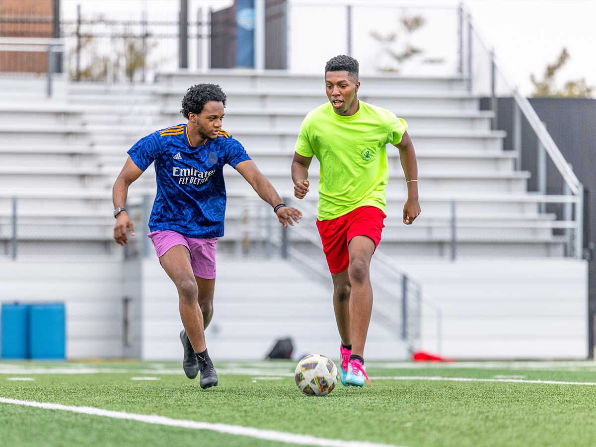 Two males students playing soccer on the field at Mediacom Stadium at Drake University.