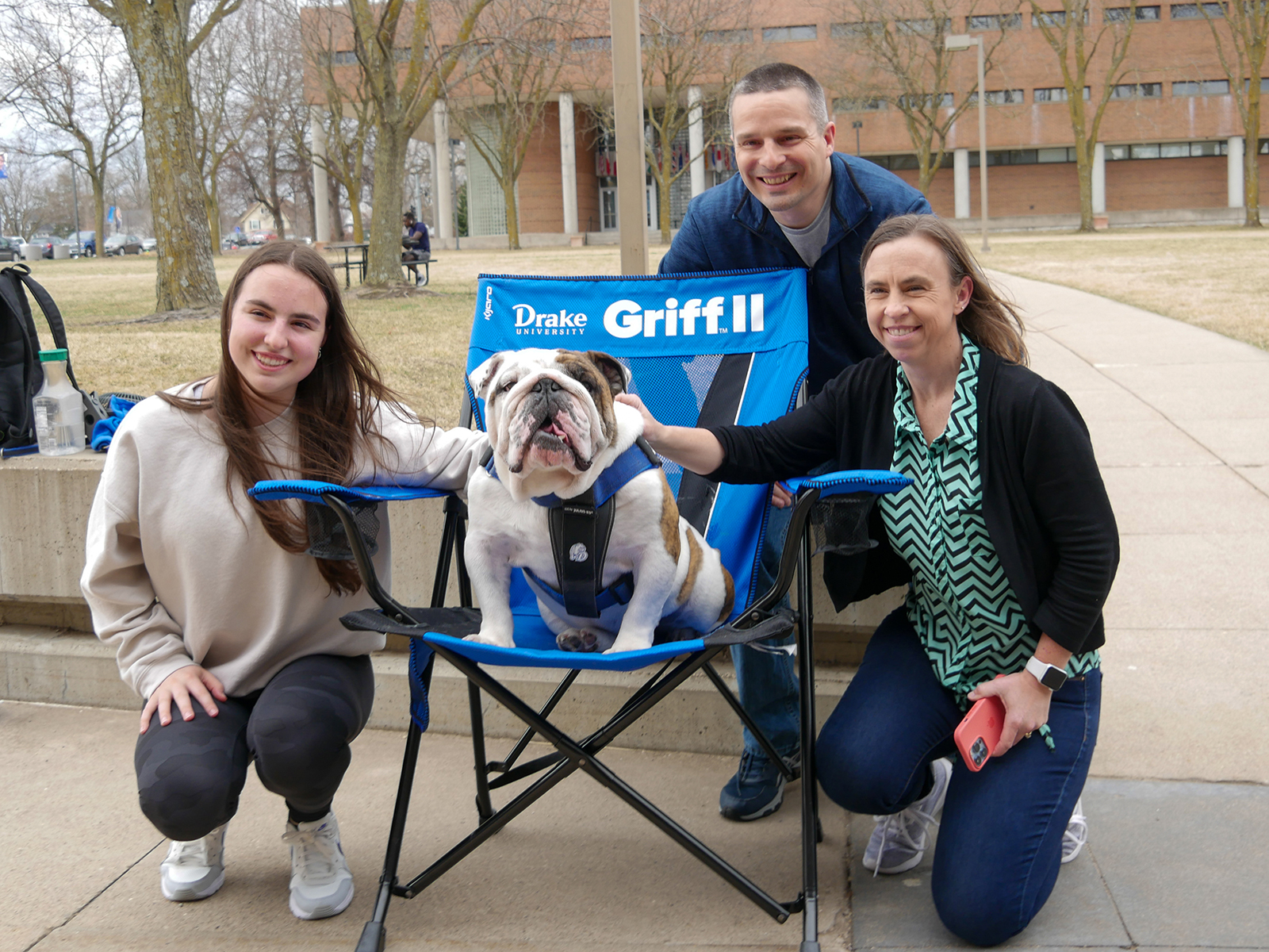 Parents and their student pet Griff II, the Drake mascot seated in a folding chair with the school logo