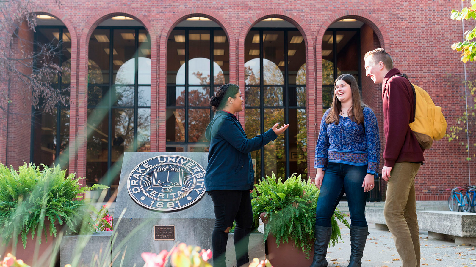 Three drake students talking in front of Cowles Library on Drake University's campus.