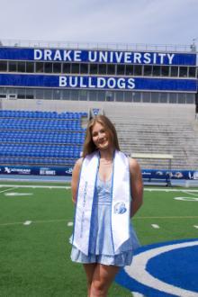 Sara Wilson standing in Drake stadium with graduation gear on