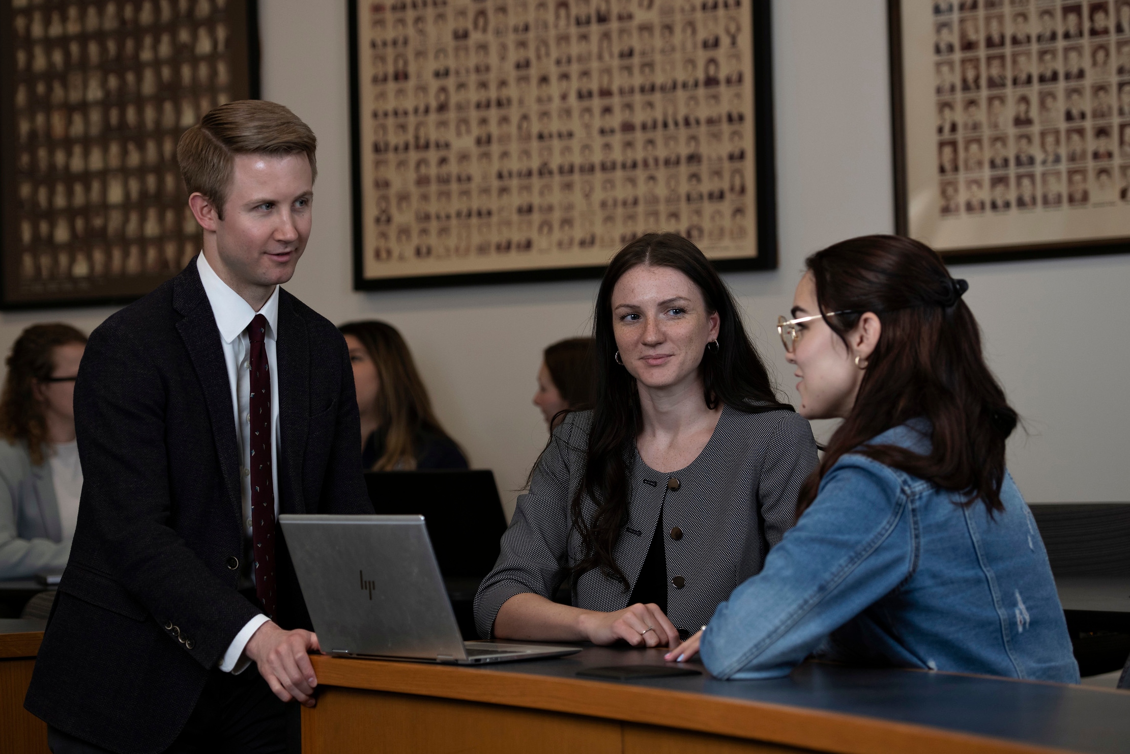 Three students from Drake's Journalism/Law 3+3 Law program review information on a laptop in a courtroom