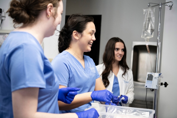 Wearing scrubs, students in Drake's 3 to a Health Sciences Degree and Joint Programs practice using medical equipment in a campus simulation lab