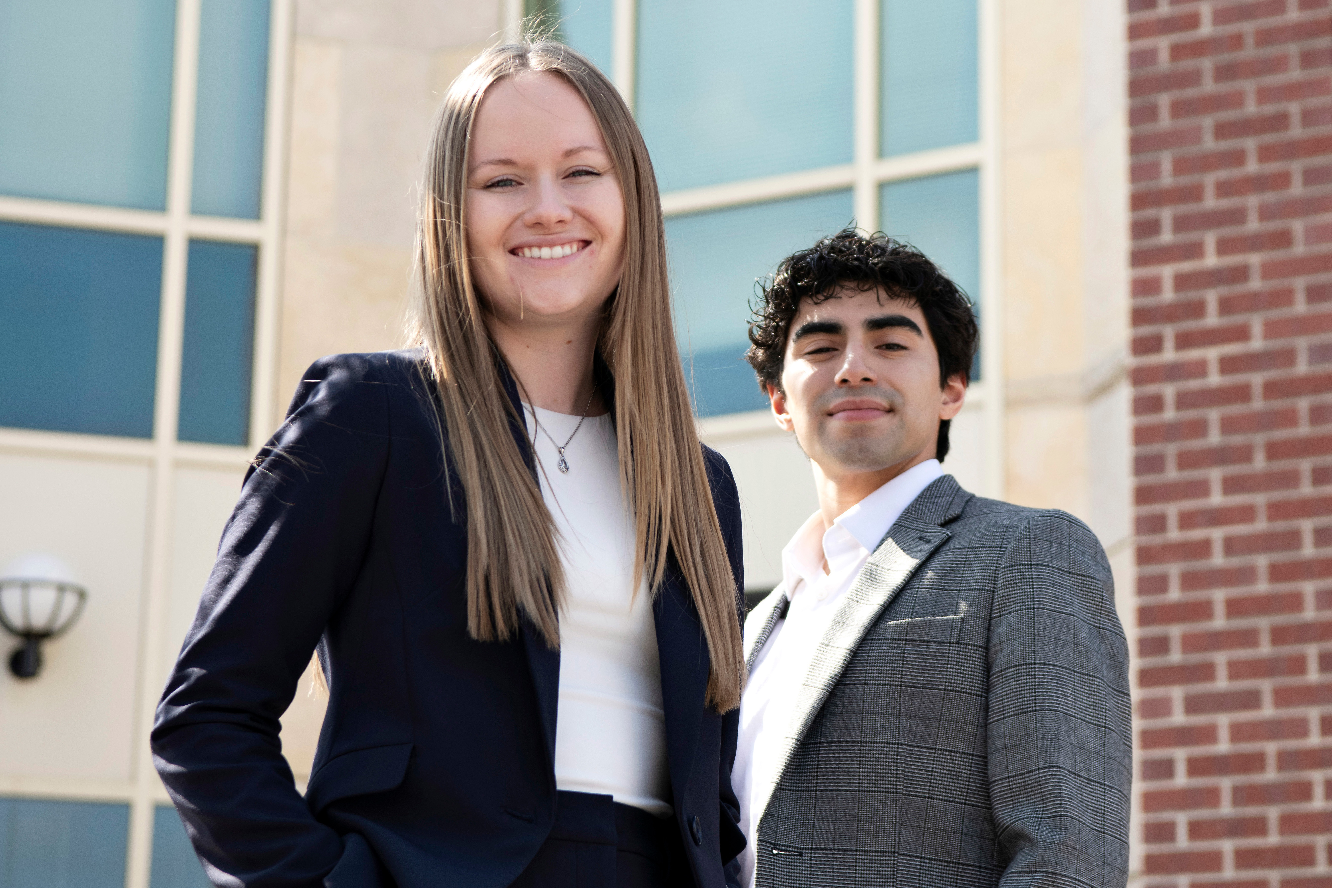 Two Drake 3+3 Law Students who started in the College of Arts and Sciences stand outdoors in front of a classroom building