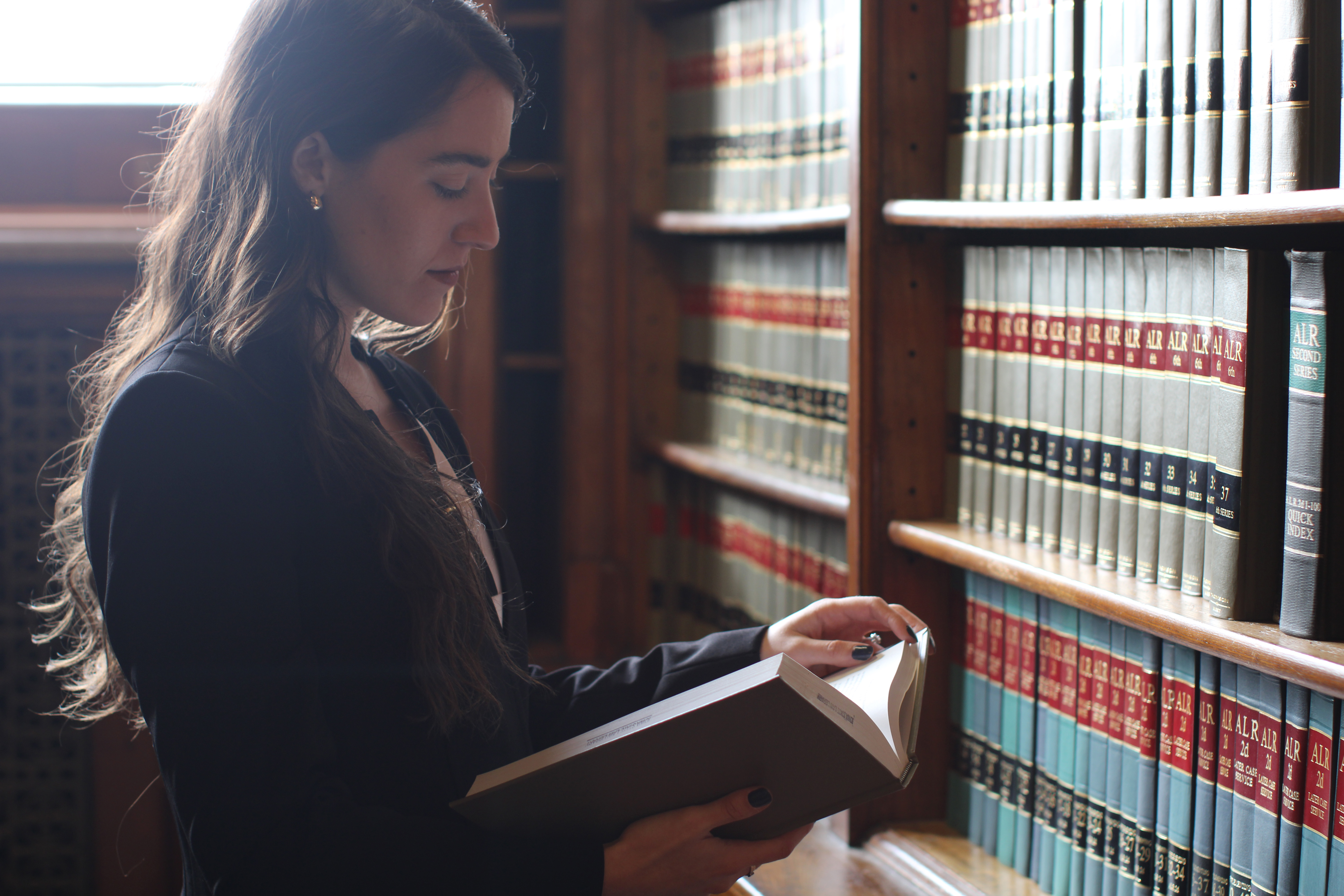 A Drake 3+3 Law student reviews books in a campus law library, conducting research for the first-year trial practicum