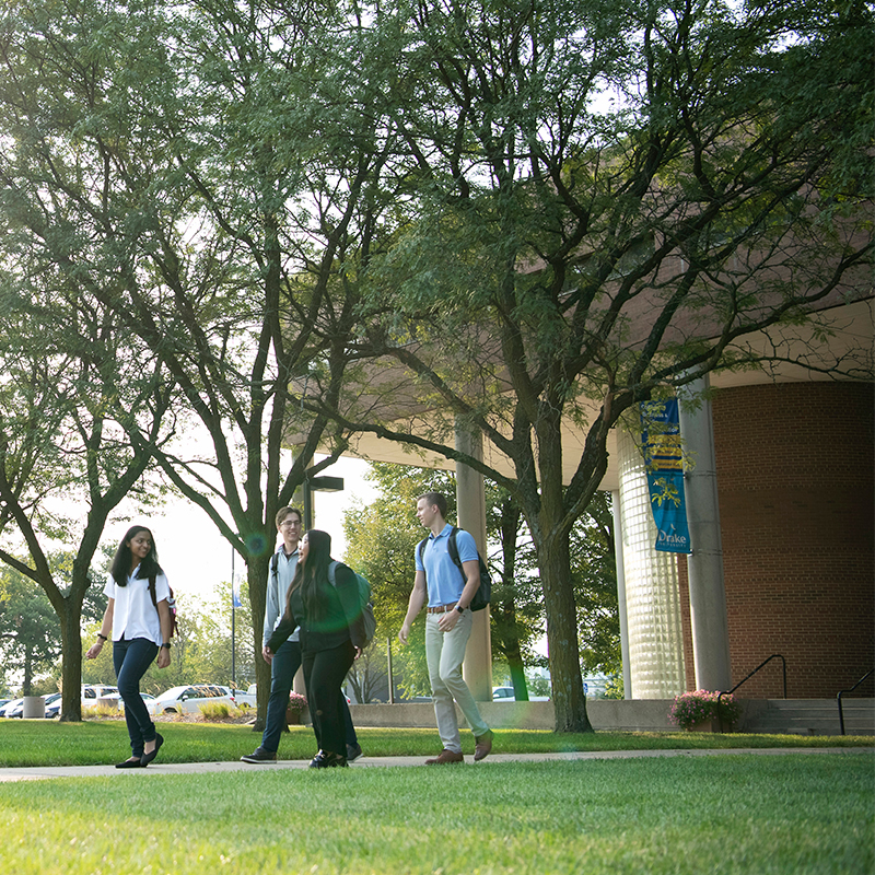 A group of Drake Business/Law 3+3 students converse and wander along an outdoor path through campus