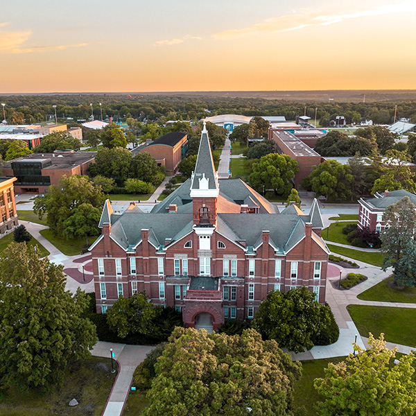 Aerial view looking over Old Main with a sunset in the background.