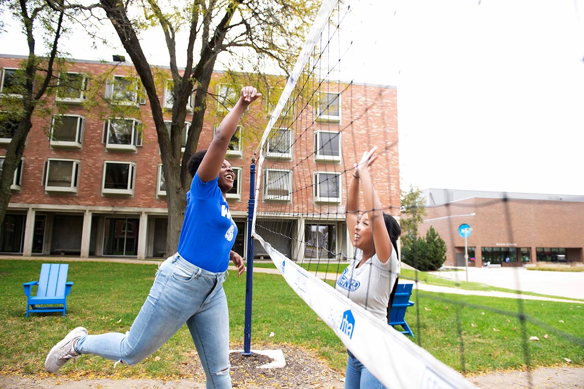 Two Drake University students playing volleyball on campus