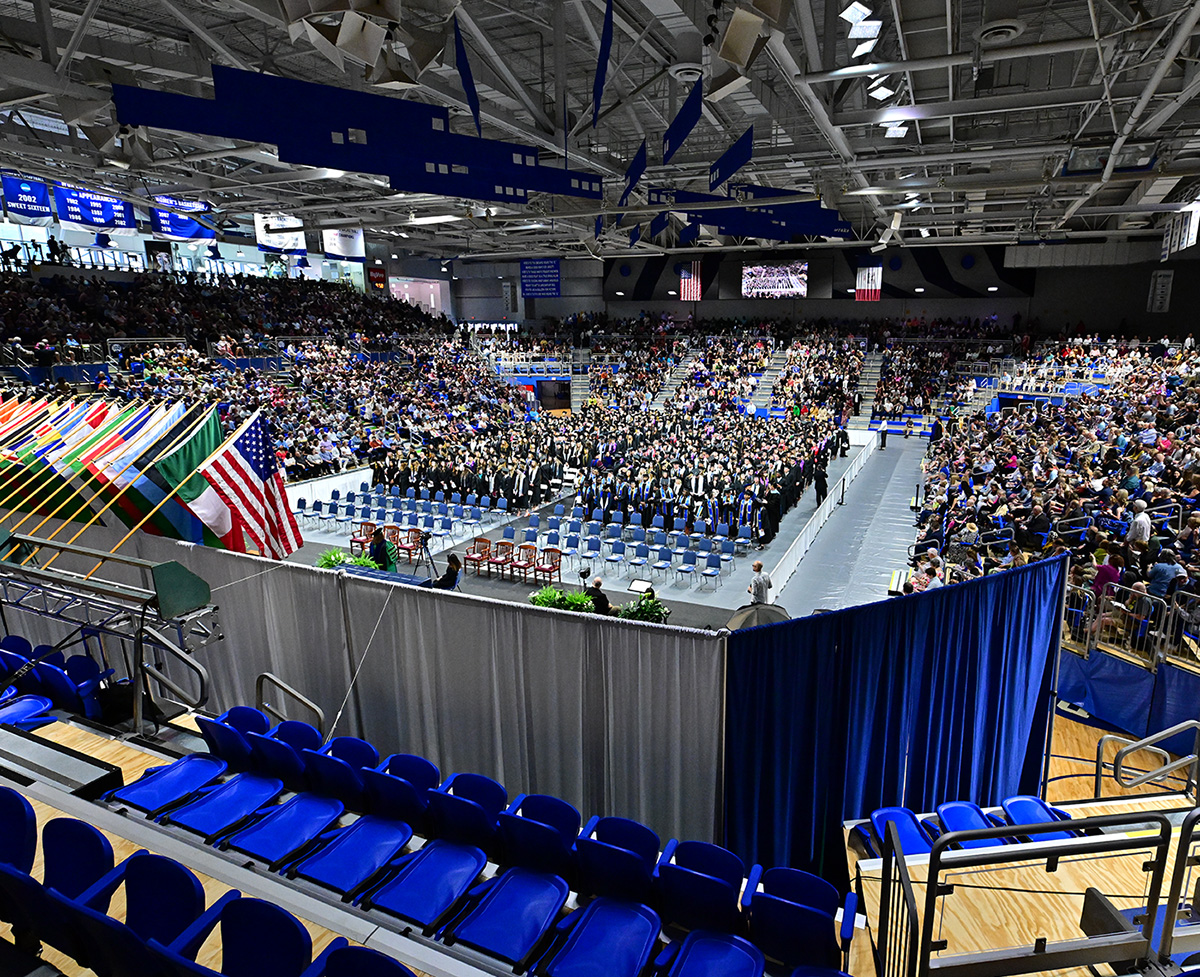View looking down into the Knapp Center before a Commencement Ceremony begins with a full crowd in attendance.