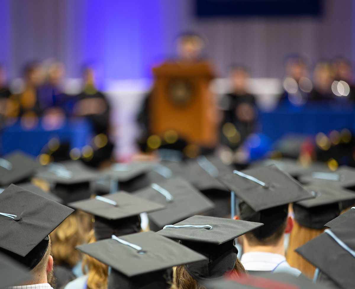 Looking up towards the stage behind graduates who are seated for a Commencement Ceremony.