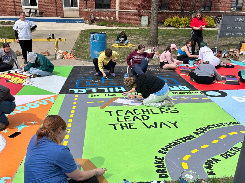 kdpi and dea students covered in paint while designing their square on painted street