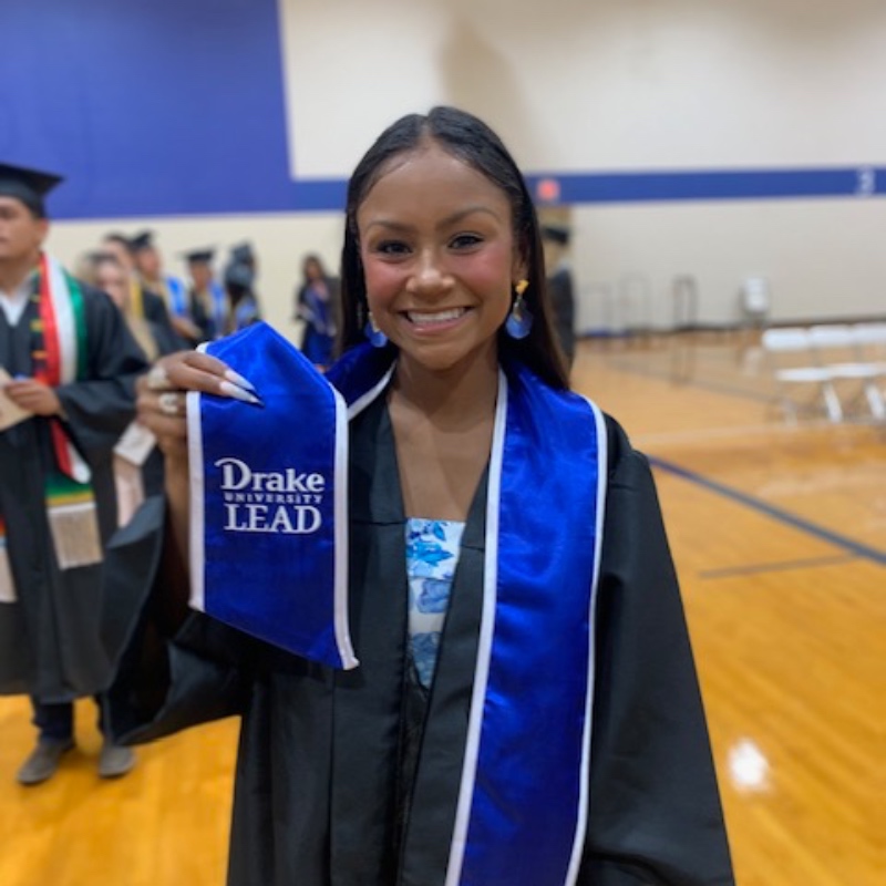 an soe student wearing her conmencement reglaia and holding up her lead stole